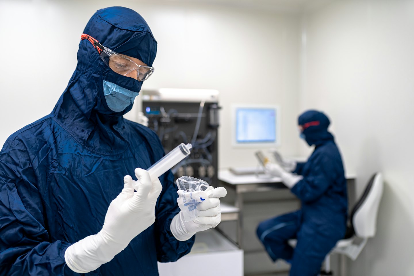 Un técnico con traje protector manipula componentes médicos en un laboratorio.